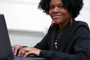 black woman smiles at her computer during online therapy in Florida with Counseling Solutions of Broward in Miramar, FL 33023. Online counseling in Florida can help you!