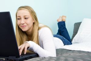 teen girl lays on her bed during an online therapy session in Florida with Counseling Solutions of Broward in Miramar, FL 33023. Online counseling in Florida can help you now!