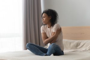 upset woman sitting on her bed after realizing she has relationship issues. She gets co-dependency recovery counseling in florida at counseling solutions of broward 33023 and online therapy or telehealth in Florida
