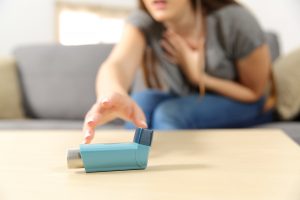 Woman sitting on a couch and reaching for her inhaler for her her health anxiety in Miramar, FL. You can start online therapy in Florida for codependency, self-sabotage, imposter syndrome, post-divorce counseling and divorce recovery and more with online counseling for women with anxiety in Miramar, FL. Meet with online therapist in Florida, Enid.