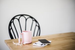 Chair at table with coffee cup, flower sprig, phone and notebook for a morning routine for healthy boundaries in Miramar, FL. You can get codependency therapy in Miramar, FL with Florida online therapist for women with anxiety, Enid.