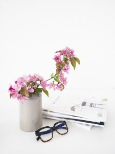 Pink flowers in a marbled vase with magazines and a pair of glasses on a white table. You can get online therapy in Florida for codependency and setting boundaries in MIramar, FL from an online therapist who specializes in relationship counseling for singles.