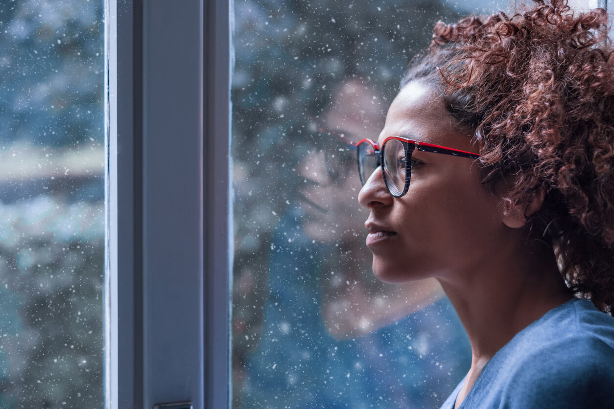 Woman looking out of rainy window. Anxiety symptoms and coping in Miramar, FL and beyond can be learned here. HSP women in Florida can get online therapy from a Florida therapist!