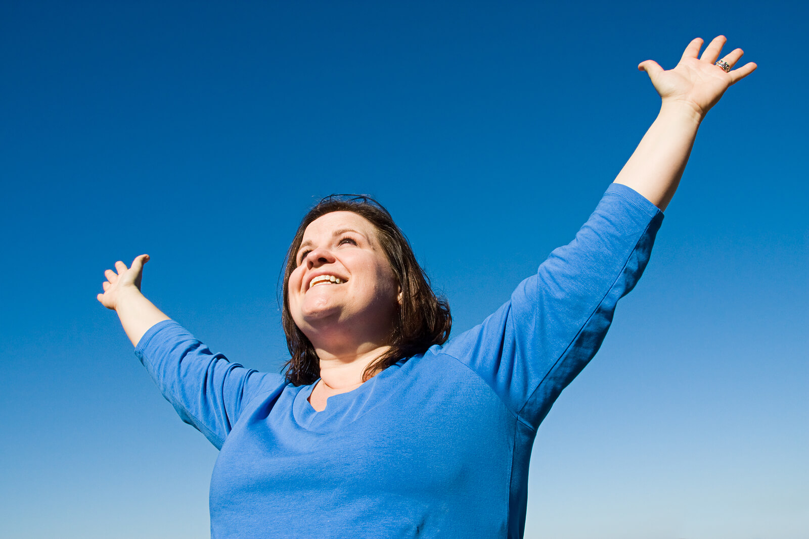 Woman with arms held high smiling as a successful HSP woman after seeking therapy for HSP women in Orlando, Miami, Miramar, etc.